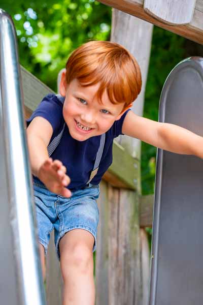 Kindergartenkind auf der Rutsche grinst Frech in die Kamera