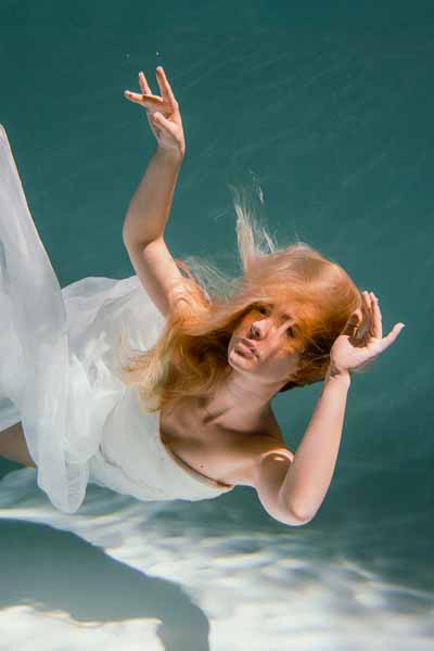 Eine Frau taucht in ihrem Brautkleid.