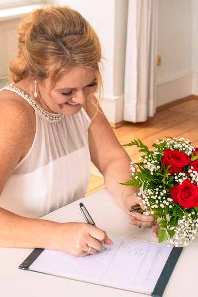 Die Braut unterschreibt beim Standesamt.